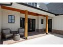 Inviting covered porch featuring wood columns, brick accents, seating area, and double doors at 247 Terrace View Dr, Acworth, GA 30101