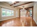 Open living room with wood floors, wooden beams, large windows, and open access to other rooms at 1830 Lost Mountain Rd, Powder Springs, GA 30127