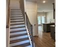 Inviting staircase with hardwood steps and black iron railing leading to an open-concept kitchen at 2405 Malster Ln, Lawrenceville, GA 30043