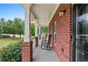 Inviting covered front porch with classic rocking chairs and brick pillars showcasing a relaxed outdoor space at 100 Coldwater Creek Dr, Mcdonough, GA 30252