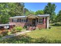 Charming brick home with a well-maintained lawn, mature trees, and inviting front porch at 1001 Rhett Nw Dr, Kennesaw, GA 30144