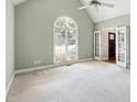 Bright bedroom with vaulted ceiling, arched window, plush carpet, and white french doors at 936 Bramble Oak Ct, Powder Springs, GA 30127