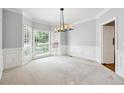 Carpeted dining room with large windows, modern light fixture, and classic white trim at 936 Bramble Oak Ct, Powder Springs, GA 30127