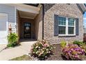 Charming front porch with brick accents and colorful flowers, creating a welcoming entrance at 5520 Allegre Pl, Cumming, GA 30028