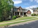 A two-story brick house with a covered porch, a two-car garage, and well-maintained landscaping at 101 Brendylynn Trce, Woodstock, GA 30188