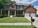 Beautiful two-story brick home featuring a covered front porch, lush lawn, and a convenient two-car garage at 101 Brendylynn Trce, Woodstock, GA 30188