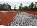 New home foundation on a spacious lot with a gravel driveway and lush trees, ready for construction at 490 Charleston Pl, Villa Rica, GA 30180