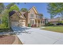 Charming home with a stone facade, a covered front porch, and a long driveway leading to an attached two-car garage at 823 Valley Dr, Canton, GA 30114