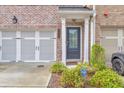Welcoming townhome entrance with brick accents, garage, and lush landscaping creating an inviting curb appeal at 6304 Brookwater Vw, Mableton, GA 30126