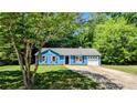 Quaint blue house with a one-car garage, framed by mature trees and lush greenery at 685 Greenhedge Dr, Stone Mountain, GA 30088