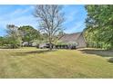 Spacious front yard of a single-story home showcasing mature trees and landscaping at 65 Macadamia Ct, Covington, GA 30016