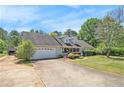 Exterior view of the single-story home featuring an attached two-car garage and a lush front yard at 65 Macadamia Ct, Covington, GA 30016