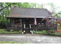 Cozy log cabin featuring a welcoming front porch, stone chimney, and a quaint, woodsy setting at 6503 Old Macon Hwy, Rex, GA 30273