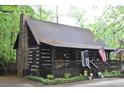 A rustic log cabin with a stone chimney and inviting front porch, set amidst a lush, green landscape at 6503 Old Macon Hwy, Rex, GA 30273