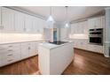 A bright kitchen featuring white cabinets, stainless steel appliances, subway tiles, an island, and hardwood floors at 4320 Royal Mustang Way, Snellville, GA 30039