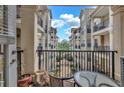 A balcony featuring a glass table, chair, and open railing, overlooking other similar units and greenery at 799 Hammond Dr # 314, Atlanta, GA 30328