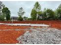 New home foundation with plumbing stubs sits on a wooded lot with gray stone around the perimeter at 492 Charleston Pl, Villa Rica, GA 30180
