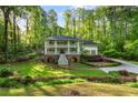 Two-story home with a double porch, surrounded by lush greenery and mature trees at 4094 Norton Se Pl, Smyrna, GA 30082