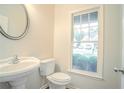 Cozy powder room features a white vanity, toilet, round mirror, and a window with natural light at 429 Gold Xing, Canton, GA 30114