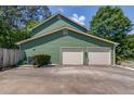 Attached two-car garage with ample driveway space, set against a backdrop of green siding and mature trees at 3987 Ivory Gables Pl, Buford, GA 30519