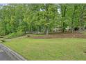 View of a charming home nestled among mature trees, with a well-maintained lawn in a quiet neighborhood at 408 Walnut Dr, Woodstock, GA 30189