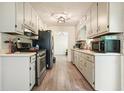 Galley kitchen with white cabinets, stainless appliances, and vinyl floors at 408 Walnut Dr, Woodstock, GA 30189