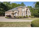 An elegant side view of a brick home showcasing manicured landscaping and a winding driveway at 4855 Regency Sw Trce, Atlanta, GA 30331