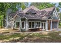 Back of the gray home showcasing a deck, screened porch, large windows, and a two-car garage at 535 Emerald Pkwy, Sugar Hill, GA 30518
