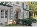 Close-up of the front entrance of the home featuring arched doorway, manicured bushes, and sconce lighting at 1658 Mount Paran Nw Rd, Atlanta, GA 30327