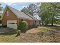 View of a house with brick and siding, a garage, and mature trees with green foliage on a sunny day at 2301 Sharon Se Ct, Conyers, GA 30013