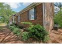 Exterior side view featuring manicured landscaping, a brick facade, and mature plantings surrounding the home at 2301 Sharon Se Ct, Conyers, GA 30013