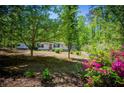 Beautiful one-story home with well-maintained landscaping with a bright red door, and is surrounded by mature trees at 1530 Mcbrayer Rd, Temple, GA 30179