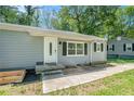 View of the home with a long sidewalk and green lawn surrounded by mature trees at 4135 Brenda Dr, Decatur, GA 30035