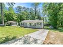 View of the home with a long concrete driveway and green lawn surrounded by mature trees at 4135 Brenda Dr, Decatur, GA 30035