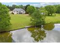 Scenic backyard of home featuring a serene pond, dock, and lush green lawn at 4790 Hyde Rd, Cumming, GA 30040