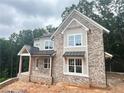 Elegant two-story house with brick and siding exterior, covered porch, and black window awnings at 1025 Liberty Springs Dr, Woodstock, GA 30188