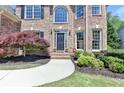 Inviting front entrance with a black door, brick walkway and manicured shrubbery at 1263 Whisperwood Ln, Lawrenceville, GA 30043