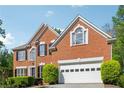 Charming two-story brick home featuring a two-car garage, arched windows, and manicured landscaping at 2160 Waters Ferry Dr, Lawrenceville, GA 30043