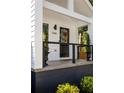 Close up view of a cozy covered front porch with black railing and lush landscaping at 1481 Almont Sw Dr, Atlanta, GA 30310