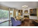 Bright living room featuring hardwood floors, a fireplace, built-in bookshelves and large windows overlooking the yard at 700 Winterwind Way, Roswell, GA 30075