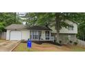 Charming split-level home featuring a stone facade, attached garage, and mature trees in the front yard at 6193 Charring Cross Ct, Lithonia, GA 30058