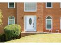 Up-close view of the brick home's white front door, complemented by blooming flowers and lush green bushes at 2253 Carrington Dr, Ellenwood, GA 30294