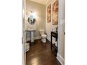 Elegant powder room with hardwood floors, pedestal sink, stylish fixtures, and modern artwork at 2262 Haventree Ct, Lawrenceville, GA 30043