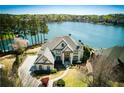Aerial view of an estate home situated on a lake with mature trees at 1160 Lake Shore Overlook, Alpharetta, GA 30005