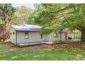 Charming exterior of home with long deck, metal roof, complemented by lush greenery and mature trees at 7580 Blacks Mill Rd, Cumming, GA 30028