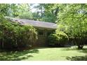 A brick house with green shutters and surrounded by mature trees and lush greenery at 5170 Chamblee Dunwoody Rd, Atlanta, GA 30338