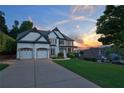 Stunning two-story home with a three-car garage, lush landscaping, and a welcoming driveway at sunset at 5420 Avonshire Ln, Cumming, GA 30040