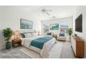 Spacious and bright primary bedroom with a ceiling fan, two chairs, and white linens with a blue throw at 3505 Chattahoochee Summit Se Ln # 25, Atlanta, GA 30339