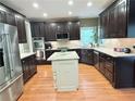 Well-lit kitchen featuring dark wood cabinets, stainless steel appliances, and a central island with a marble countertop at 6795 Preston Glen Dr, Alpharetta, GA 30005