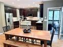 Bright kitchen with dark cabinets, stainless steel appliances, island, and open access to a dining area and screened porch at 6795 Preston Glen Dr, Alpharetta, GA 30005